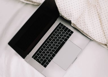Beyaz çarşaflar üzerinde yatakta Laptop. Evde çalışma konsepti. Düz döşeme, üst görünüm, yaşam tarzı, minimalist çalışma alanı arka plan. 