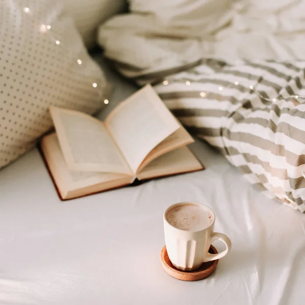ベッドシーツとコーヒー1杯の上に本を開きます。おはようございます。朝食の時間だベッドで朝食。フラットレイ — ストック写真