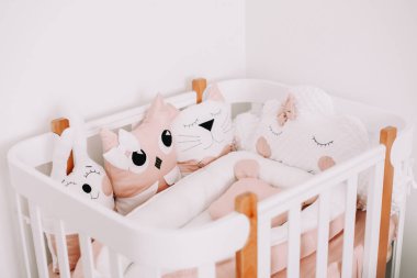 Rahat beşik ile şık bebek odası iç. Renkli dekoratif yastıklar ile İskandinav tarzında rahat çocuk yatak odası.