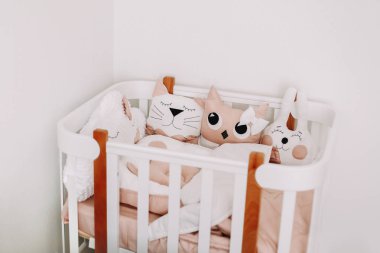 Bir kız bebek için tatlı kreş odası süslemeleri. Rahat beşik ile şık bebek odası iç. Renkli dekoratif yastıklar ile İskandinav tarzında rahat çocuk yatak odası.