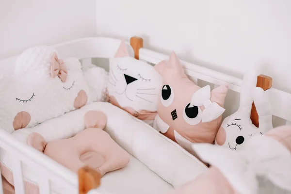 Elegante interior de la habitación del bebé con cuna cómoda. Acogedora habitación infantil de estilo escandinavo con almohadas decorativas de colores . — Foto de Stock