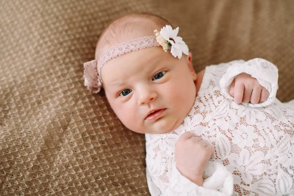 Primer plano encantadora niña recién nacida en una manta. Un retrato de una hermosa niña recién nacida con una diadema. Foto de primer plano —  Fotos de Stock