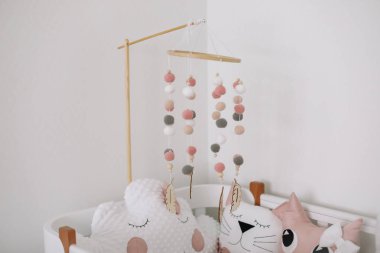 Bebek odasının güzel iç mekanı. Bebek odasında yastıklı beyaz beşik ve pembe battaniye. beyaz duvara karşı yatakta pembe yatak