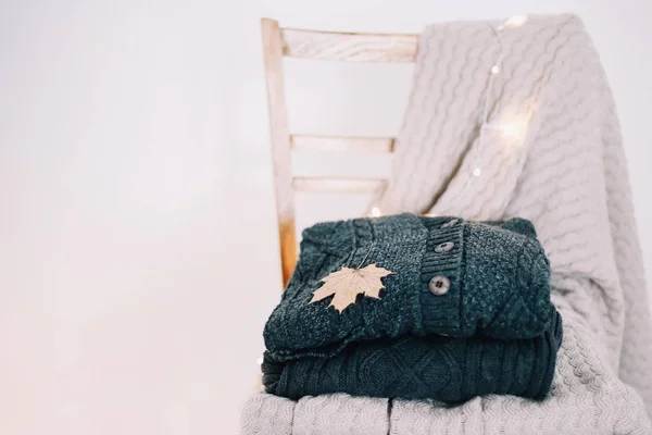 Stack of cozy knitted sweaters on a wooden chair.  Autumn and winter, leisure concept. Cozy, comfy, soft.