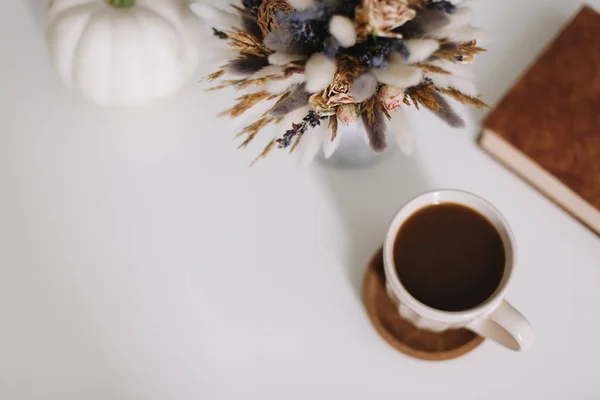 Top view of workspace or office desk. Cup of coffee, book and dried flowers at white background. Flat lay, top view — Stock Photo, Image