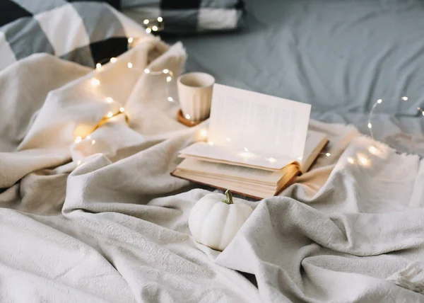 Pequeno-almoço na cama. Cama com colcha, lençóis cinzentos e travesseiros, um copo e um livro. fim de semana preguiçoso. Doce lar . — Fotografia de Stock