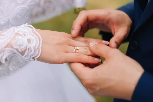 Handen van bruid en bruidegom die een trouwring dragen. Huwelijksvoltrekking. Pasgetrouwden — Stockfoto