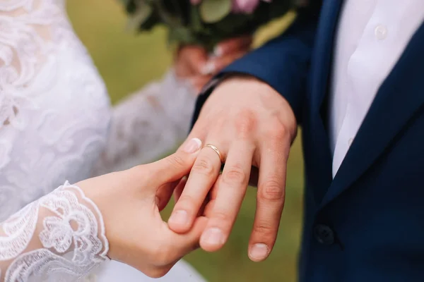 Handen van bruid en bruidegom die een trouwring dragen. Huwelijksvoltrekking. Pasgetrouwden — Stockfoto