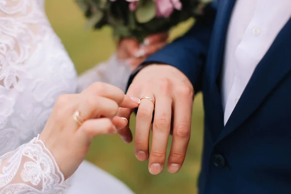 Handen van bruid en bruidegom die een trouwring dragen. Huwelijksvoltrekking. Pasgetrouwden — Stockfoto