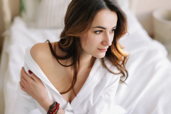 Portrait of a young beautiful woman in bed in the morning at home. Beautiful brunette in the bedroom. Good morning. Lifestyle. — Stock Photo, Image