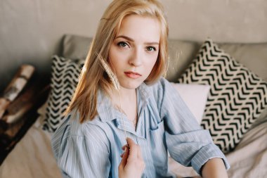 Sabahları yatakta yatan genç ve güzel bir kadının portresi. İskandinav iç mekanındaki sarışın kız. İyi sabahlar. Yaşam biçimi.