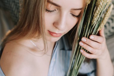 Sabahları yatakta yatan genç ve güzel bir kadının portresi. İskandinav iç mekanındaki sarışın kız. İyi sabahlar. Yaşam biçimi.