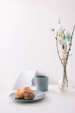 Masada şekerleme ve çiçek olan bir fincan kahve. Romantik bir sabah. Lezzetli bir kahvaltı. Düz konum, üst görünüm, kopyalama alanı.