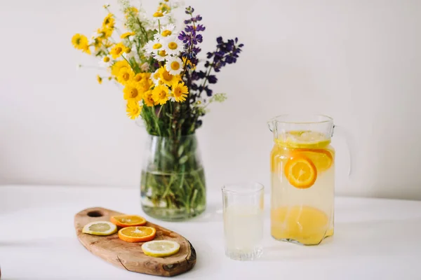 Summer concept. Bouquet of wild natural flowers. Homemade lemonade with orange and lemon. Healthy  fresh cool beverage — Stock Photo, Image