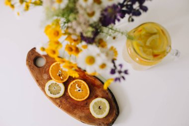 Yaz kavramı. Masadaki yabani çiçek buketi. Portakal ve limonlu ev yapımı limonata. Turunçgilli sağlıklı bir içecek.