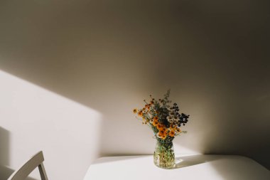 Renkli yaz ortası kır çiçekleri. Masanın üzerindeki vazoda bir buket doğal çiçek, seçici bir odak. Yaz duvar kağıdı