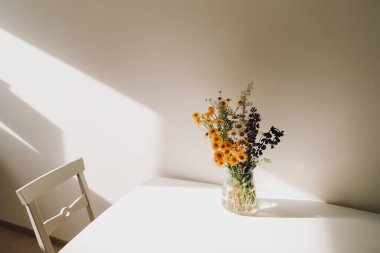 Renkli yaz ortası kır çiçekleri. Masanın üzerindeki vazoda bir buket doğal çiçek, seçici bir odak. Yaz duvar kağıdı