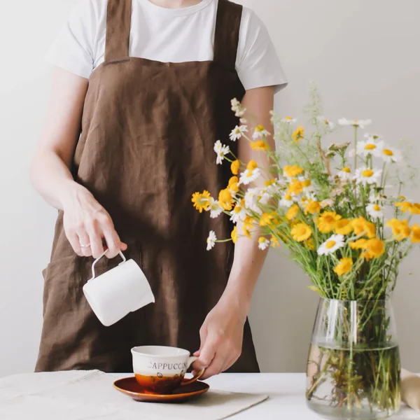 Mulher fazendo café e café da manhã na cozinha. Mulher barista derramando leite em xícara de café, fazendo café, arte latte — Fotografia de Stock