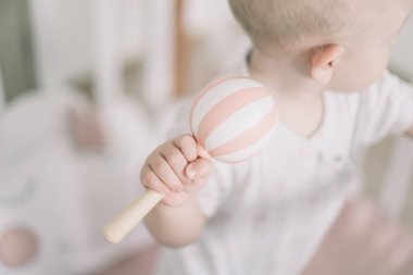 Bebek tahta oyuncakla oynuyor. Elleri tahta bebek çıngırağı tutuyor. Plastik olmayan çevre dostu oyuncaklar konsepti. Metin için boşluk. 