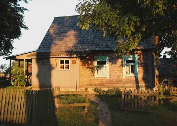 Stary drewniany dom we wsi. Dom na Białorusi. Widok rustykalny etniczny dom na zachód słońca. krajobraz wiejski — Zdjęcie stockowe