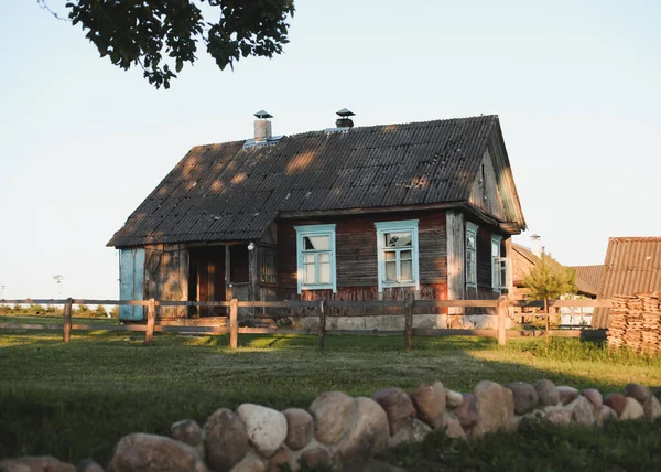 Starý dřevěný dům ve vesnici. Farmu v Bělorusku. Pohled na venkovský etnický dům při západu slunce. venkovská krajina — Stock fotografie