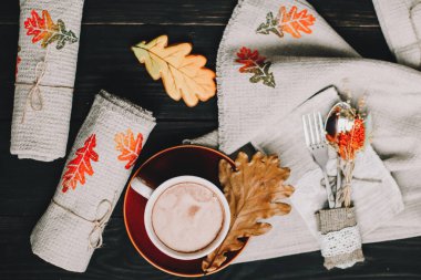 Çarşaf mutfak havluları, tekstil peçetesi ve ahşap bir masada kahve fincanı olan kırsal bir sonbahar. Koyu kırsal yaşam.
