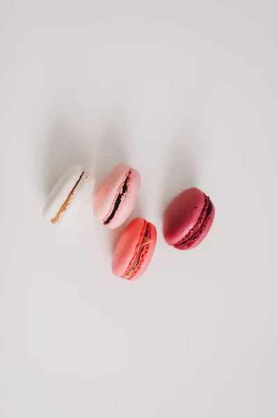 Tasty macarons cookies and flowers on white background. Colorful french desserts. Copy space, minimal style, flat lay, top view. — Stock Photo, Image