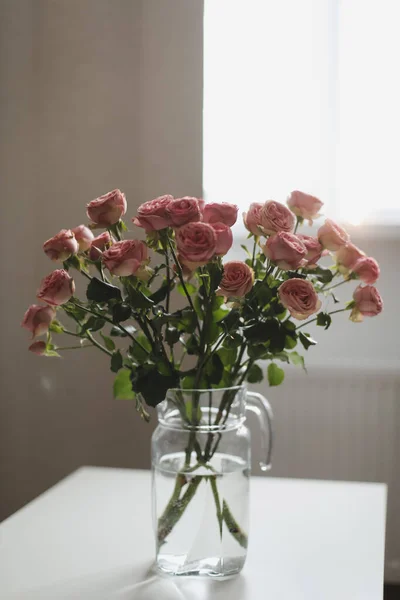 Pink roses flowers bouquet in glass vase against the window. Holiday celebration concept. Interior decoration Stock Image