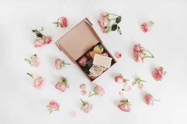 Beyaz arka planda pembe güller ve taç yaprakları olan doğal ev yapımı organik sabun. Spa konsepti, üst görünüm, düz çizgi 
