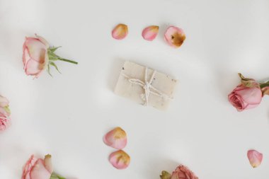 Beyaz arka planda pembe güller ve taç yaprakları olan doğal ev yapımı organik sabun. Spa konsepti, üst görünüm, düz çizgi 