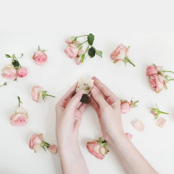 Hands holding natural soap bar with flowers on white background. Spa, Bath, Hygienic concept. Top View, Flatlay