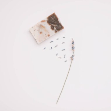 Beyaz arka planda el yapımı sabun ve lavanta, üst manzara. Lavanta çiçekleri vücut bakımı için doğal sabunlar üretir. 