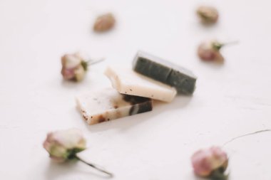 Beyaz arka planda kuru güller olan sabun barları. Gül tomurcuklu el yapımı çiçek sabunu. Doğal kozmetikler. düz yatış, üst görünüm