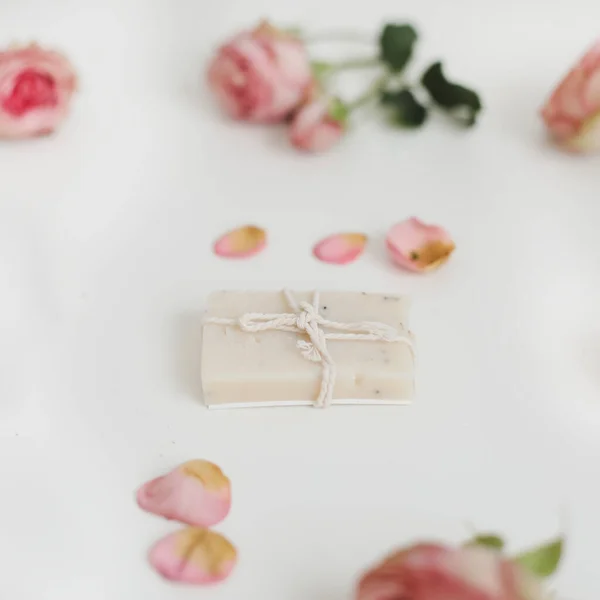하얀 배경에 마른 장미가 깔려 있는 비누바. 장미 봉오리가 달린 손으로 만든 꽃 비누. 천연 화장품. 위에서 내려다 본 평평 한 모습 — 스톡 사진
