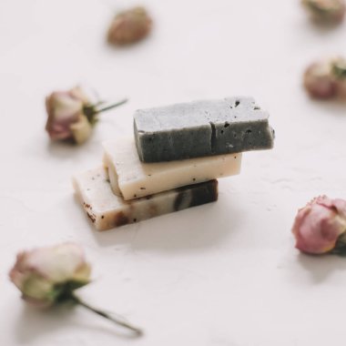 Beyaz arka planda kuru güller olan sabun barları. Gül tomurcuklu el yapımı çiçek sabunu. Doğal kozmetikler. düz yatış, üst görünüm