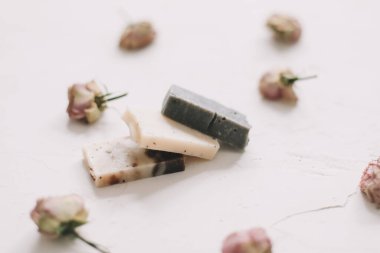 Beyaz arka planda kuru güller olan sabun barları. Gül tomurcuklu el yapımı çiçek sabunu. Doğal kozmetikler. düz yatış, üst görünüm