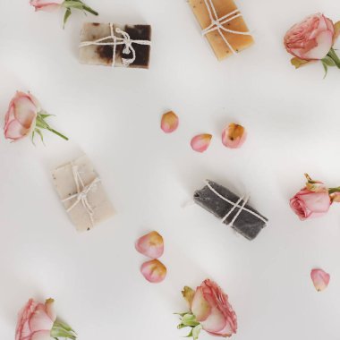 Beyaz arka planda kuru güller olan sabun barları. Gül tomurcuklu el yapımı çiçek sabunu. Doğal kozmetikler. düz yatış, üst görünüm