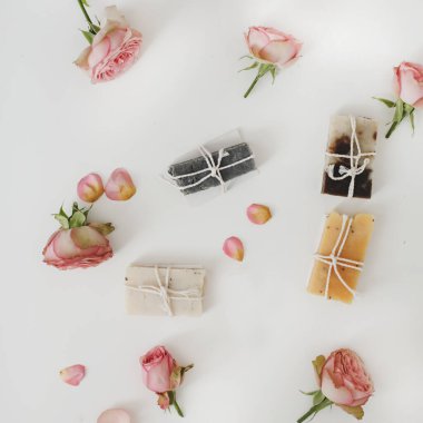 Beyaz arka planda kuru güller olan sabun barları. Gül tomurcuklu el yapımı çiçek sabunu. Doğal kozmetikler. düz yatış, üst görünüm