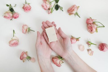 Beyaz arka planda çiçekli sabun çubuğu tutan kadın elleri. Doğal kozmetik. Üst Manzara, düz uzanma