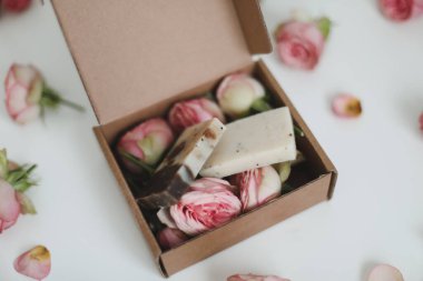Doğal ev yapımı sabun kalıpları ve beyaz arka planda gül çiçekleri olan hediye kutusu. Tatil hediyesi, açılış hediyesi, üst görünüm. 