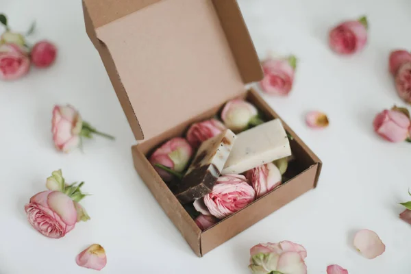 Caja de regalo con barras de jabón caseras naturales y flores de rosas sobre fondo blanco. Regalo de vacaciones, regalo de apertura, vista superior. — Foto de Stock