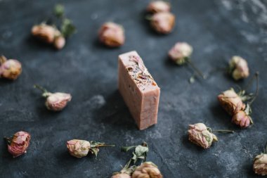 Ev yapımı çiçek sabunu. Koyu arkaplanda doğal sabun ve gül çiçekleri. Spa konsepti, vücut bakım ürünleri. Düz yatış, üst görünüm