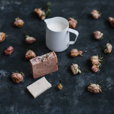 Ev yapımı çiçek sabunu. Koyu arkaplanda doğal sabun ve gül çiçekleri. Spa konsepti, vücut bakım ürünleri. Düz yatış, üst görünüm