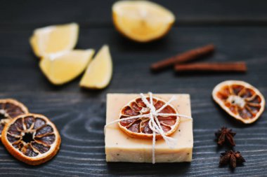 Koyu arkaplanda kurutulmuş portakal dilimleri ve tarçın olan doğal el yapımı sabun. Spa, vücut ve cilt bakımı kavramı.  