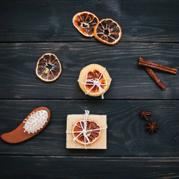 Koyu arkaplanda kurutulmuş portakal dilimleri ve tarçın olan doğal el yapımı sabun. Spa, vücut ve cilt bakımı kavramı.  
