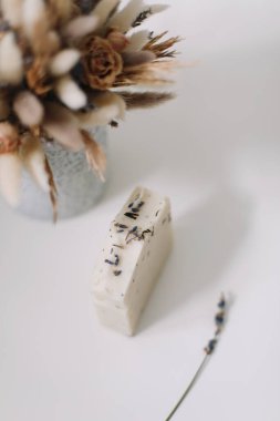 Beyaz arka planda doğal ev yapımı sabunluklar ve çiçekler. Spa konsepti, vücut bakım ürünleri. Tatil hediyesi, üst görünüm düzlük. 