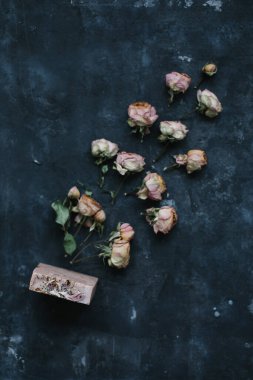 Ev yapımı çiçek sabunu. Karanlık arka planda doğal sabun ve çiçekler. Spa konsepti, doğal kozmetik. Düz yatış, üst görünüm