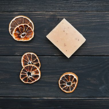 Koyu arkaplanda kurumuş portakal dilimleri olan doğal el yapımı sabun. Vücut ve cilt bakımı. Düz yatıyordu. Metin için boşluk, üst görünüm