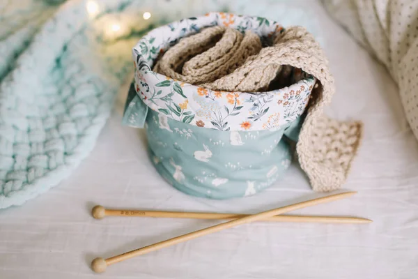 Tricot à l'intérieur confortable de la maison. Humeur d'hiver ou de Noël. Panier avec fil, aiguilles au soleil chaud. Concept de passe-temps, de loisirs. — Photo