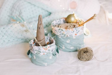Oyuncak sepetleri, iplikler, iğneler, örülmüş giysiler, arka planda Bokeh lambaları. İçerisi çocuk odası gibi. Kış ya da Noel havası